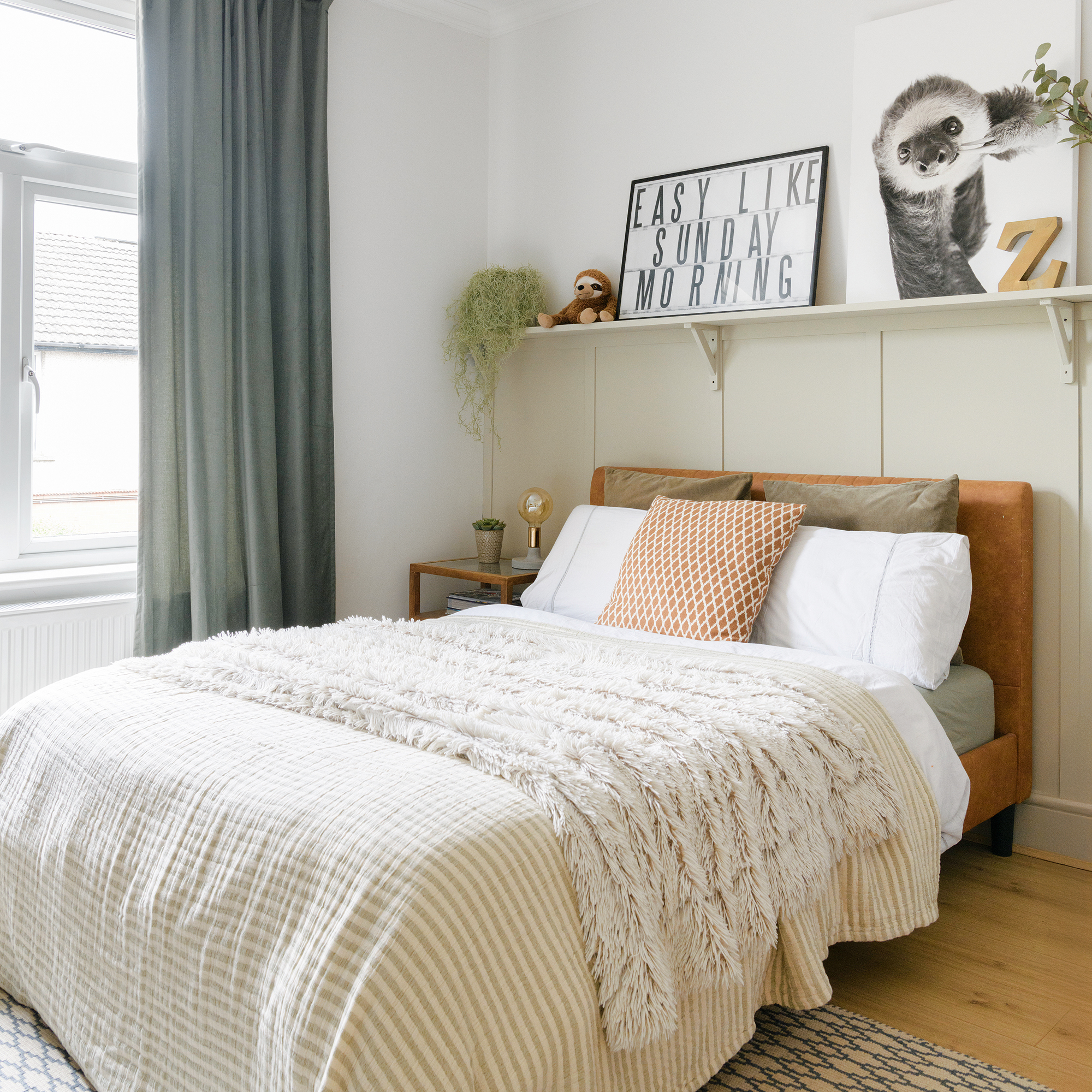 a neutral coloured bedroom with wooden panelling on the walls, and sage green curtains