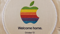 A multicolour crotchet Apple logo on beige cloth with writing beneath that reads "Welcome home. October 13"