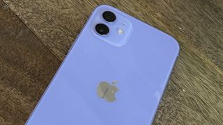 An iPhone 12 in purple on a wooden floor