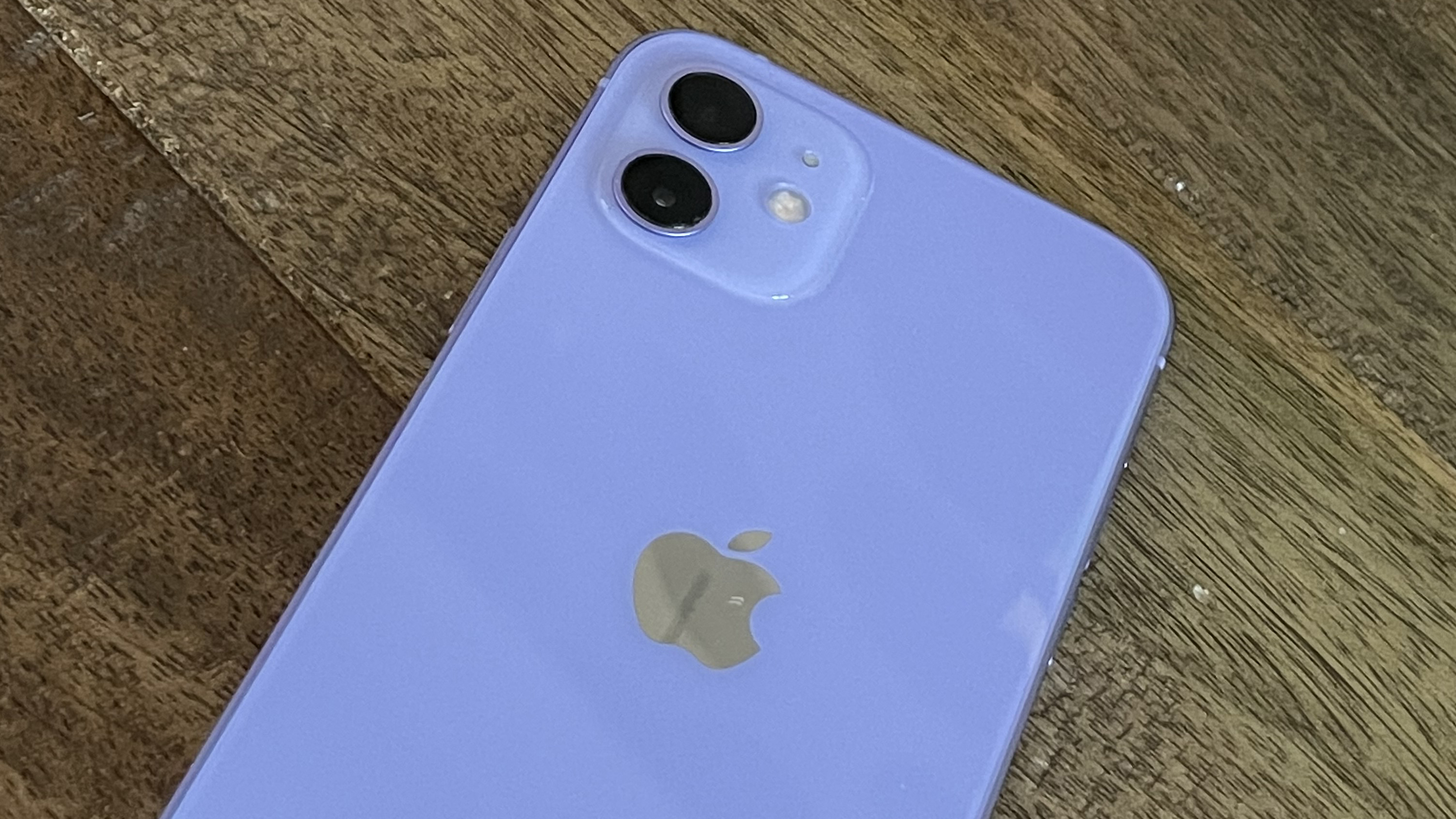 An iPhone 12 in purple on a wooden floor