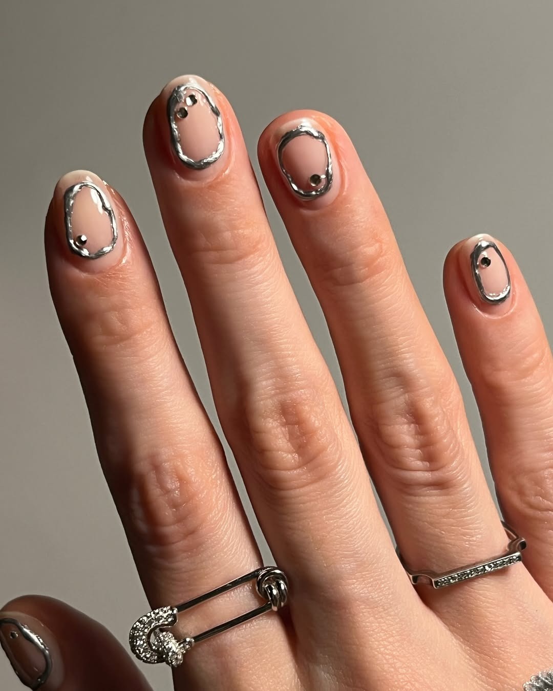 Molten metal silver nail art against a natural nail base.
