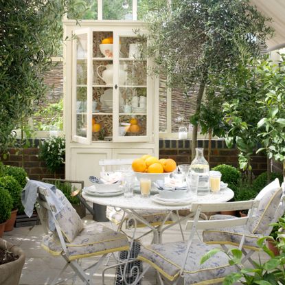 A conservatory with lots of plants and a white bistro set