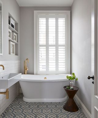 An example of white bathroom ideas showing a small white bathroom with a compact bath and geometric floor tiles