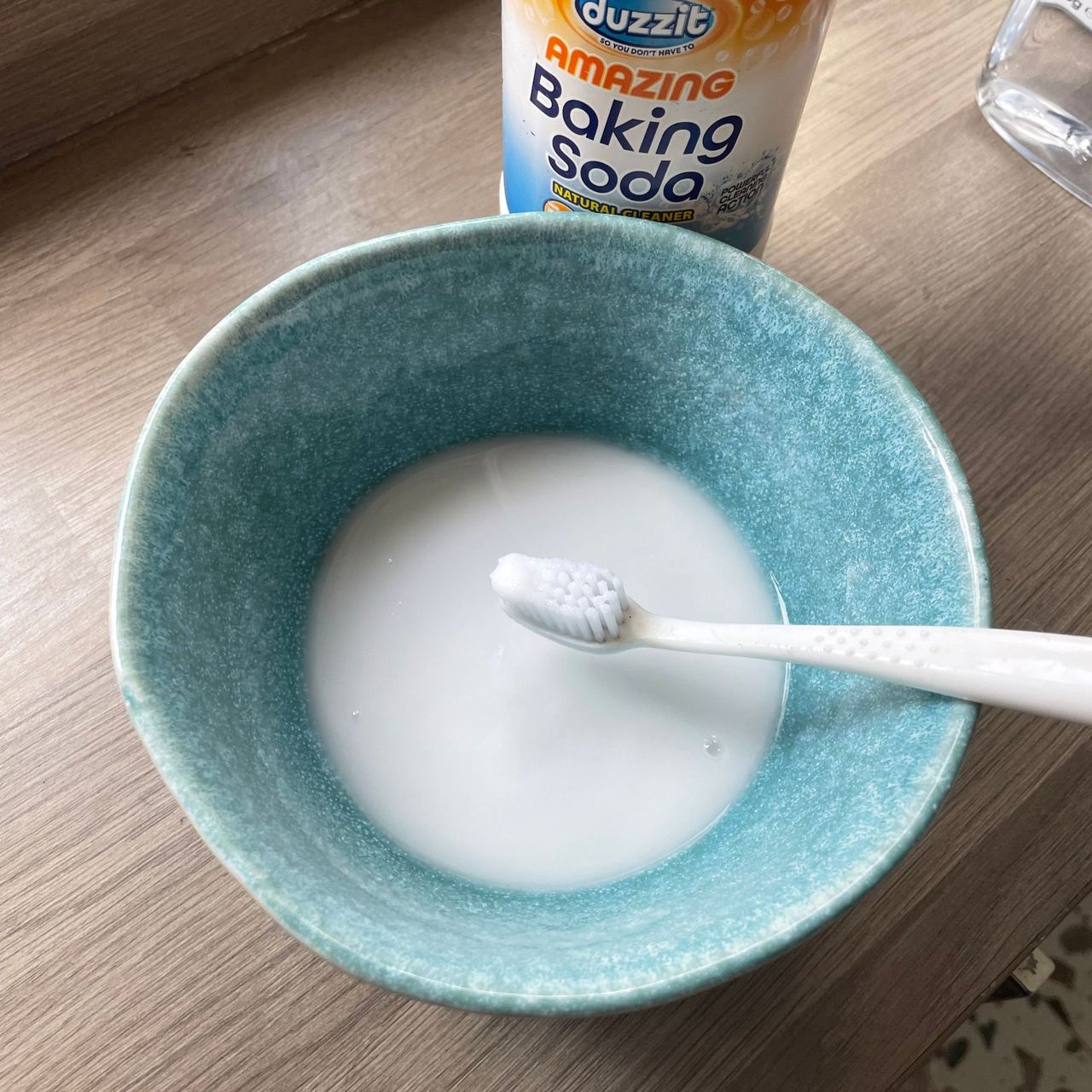 Paste of bicarb and water in a blue bowl with a toothbrush laying on top
