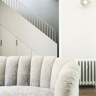 A quilted white boucle sofa with a staircase in the background