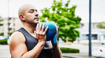 A man performing a squat with a kettlebell