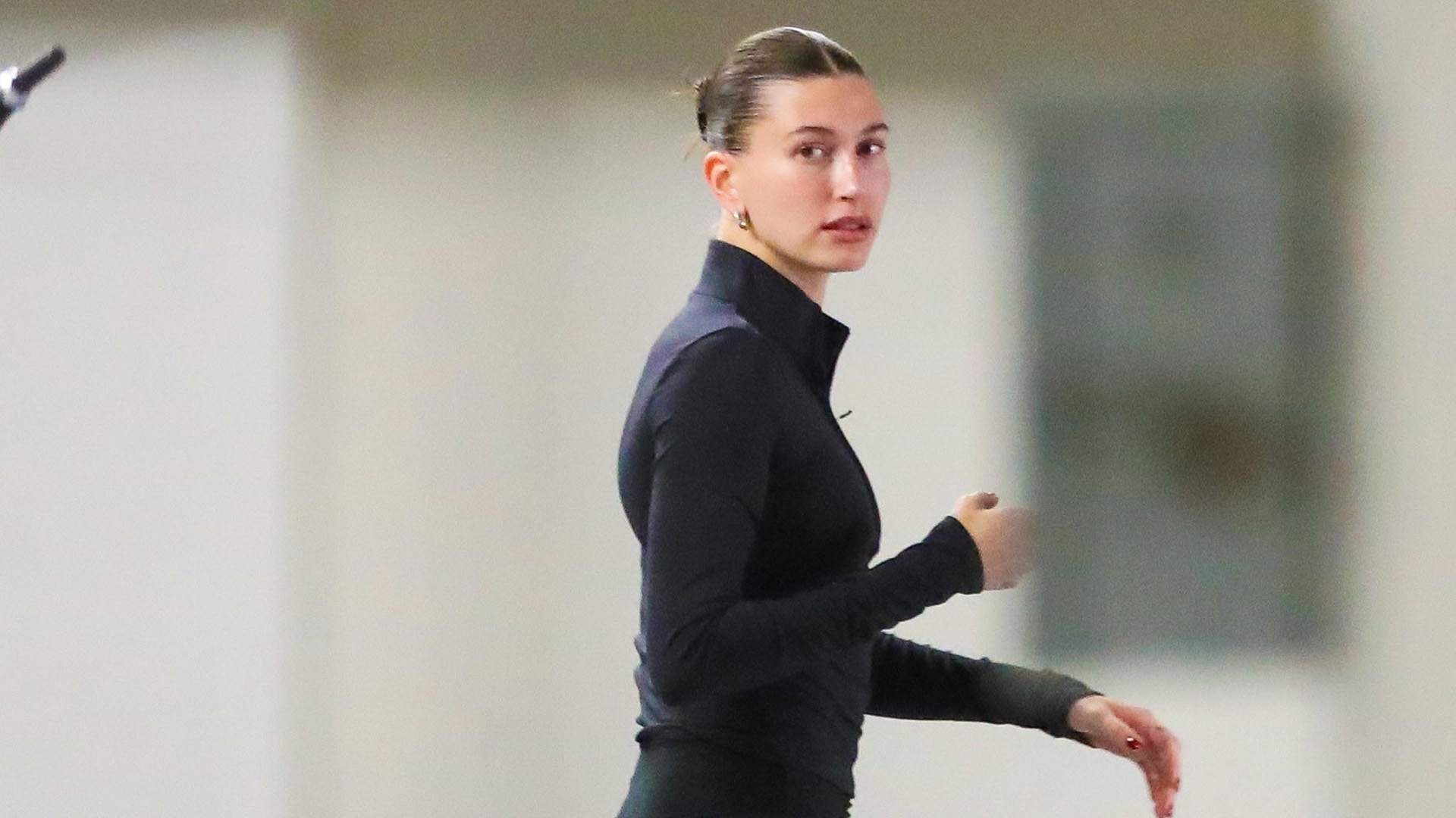 Hailey Bieber wearing a mock-neck jacket, flared Alo leggings, and two-tone sneakers