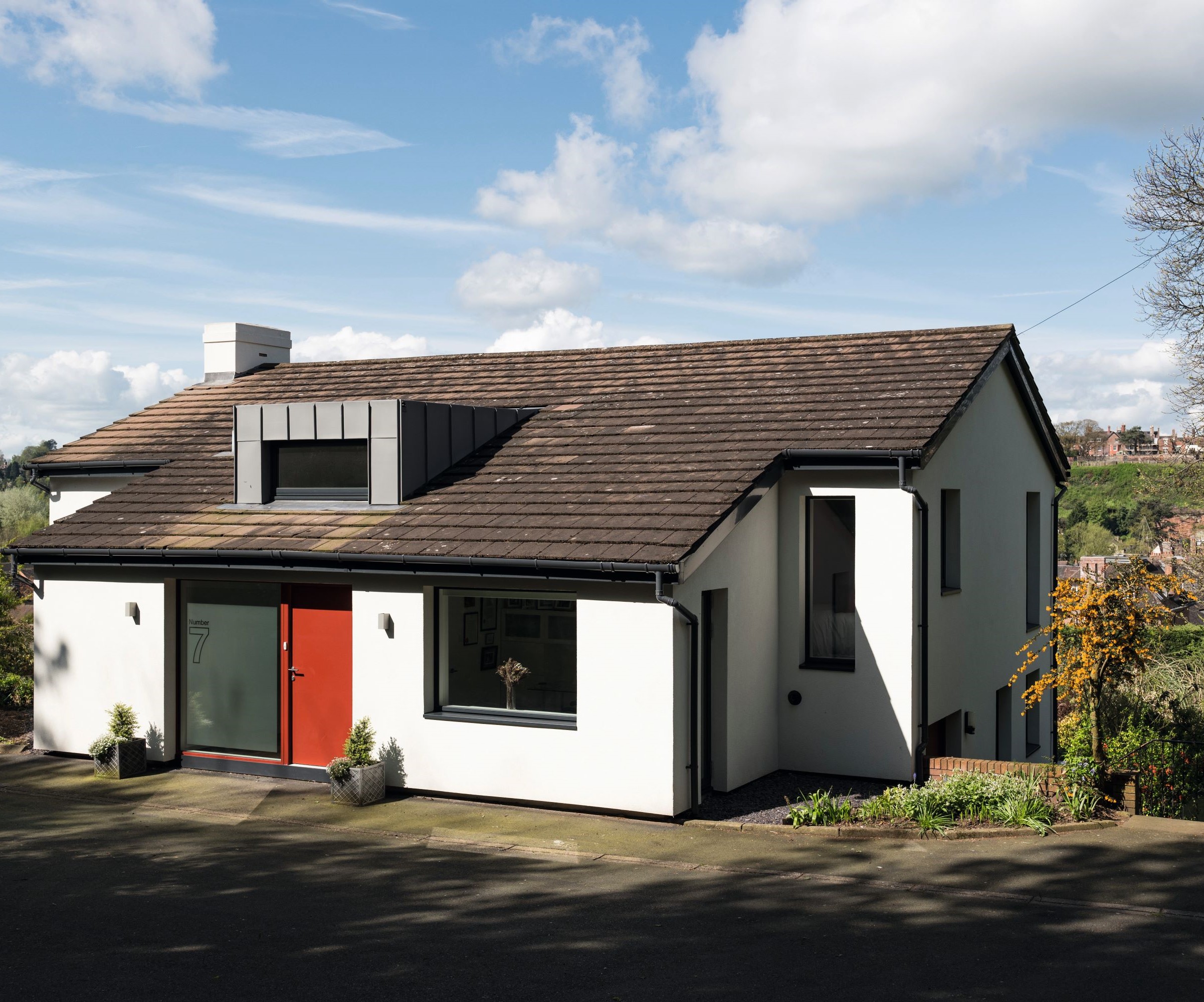 A rendered home with orange front door and metal clad dormer