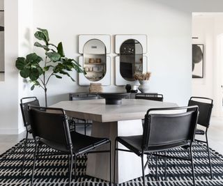 Modernist dining room with hexagonal marble dining table and black leather chairs and large black and white rug