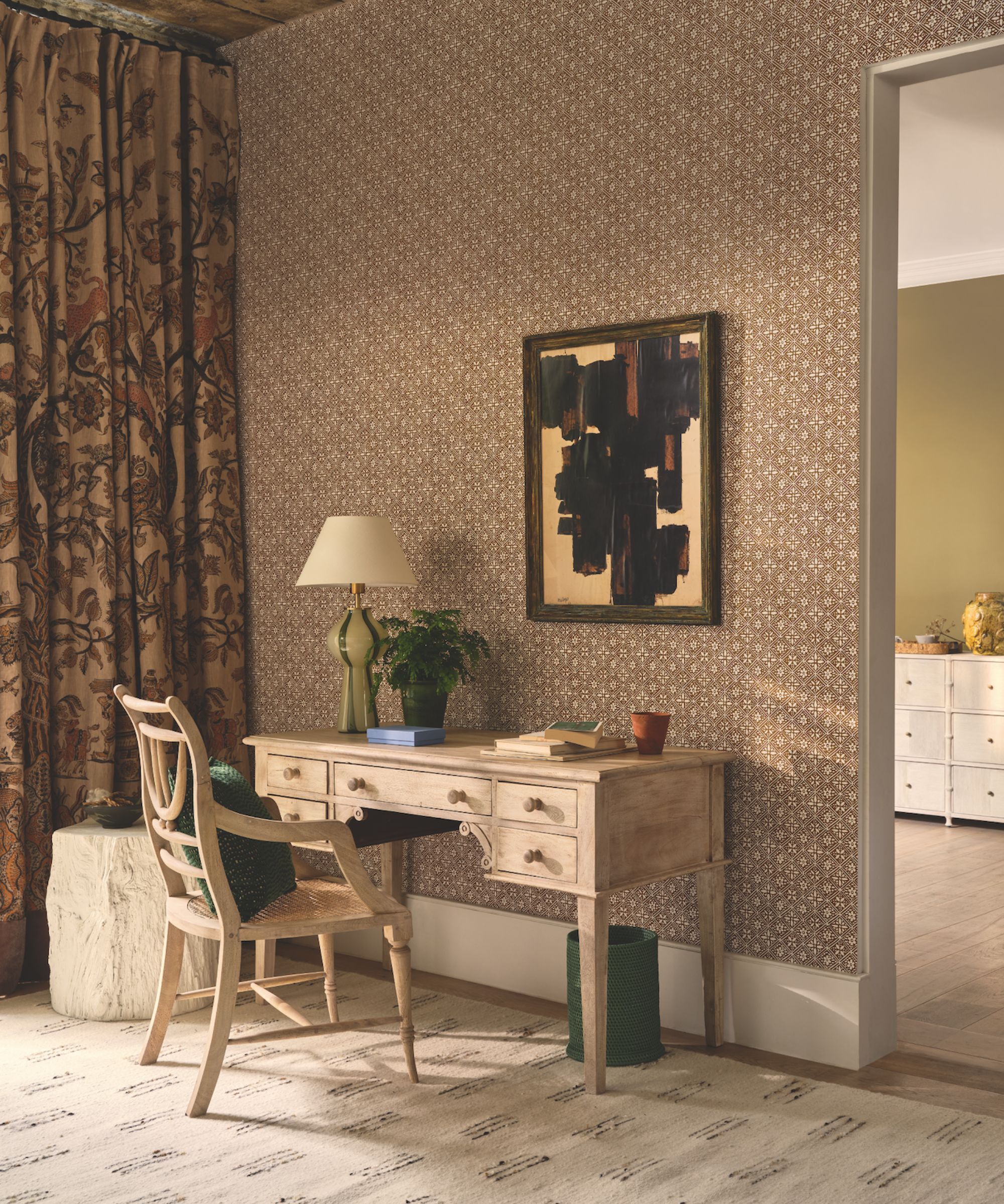 A neutral office space with patterned wallpaper and rustic limewashed furniture