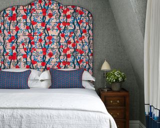 A bold Kit Kemp blue and red patterned headboard in a small bedroom layout.