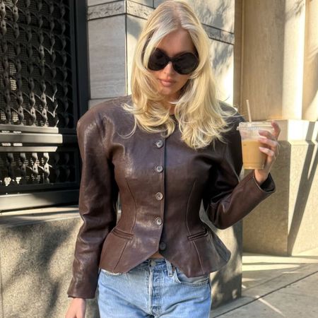 elsa wears a brown leather jacket and large sunglasses.