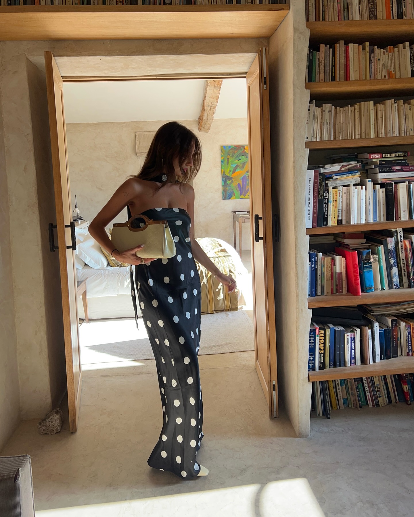Clem in polkadot dress and holding woven baguette bag