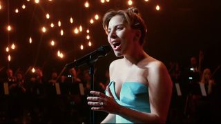 Lady Gaga singing with a full orchestra behind her in A Star Is Born.