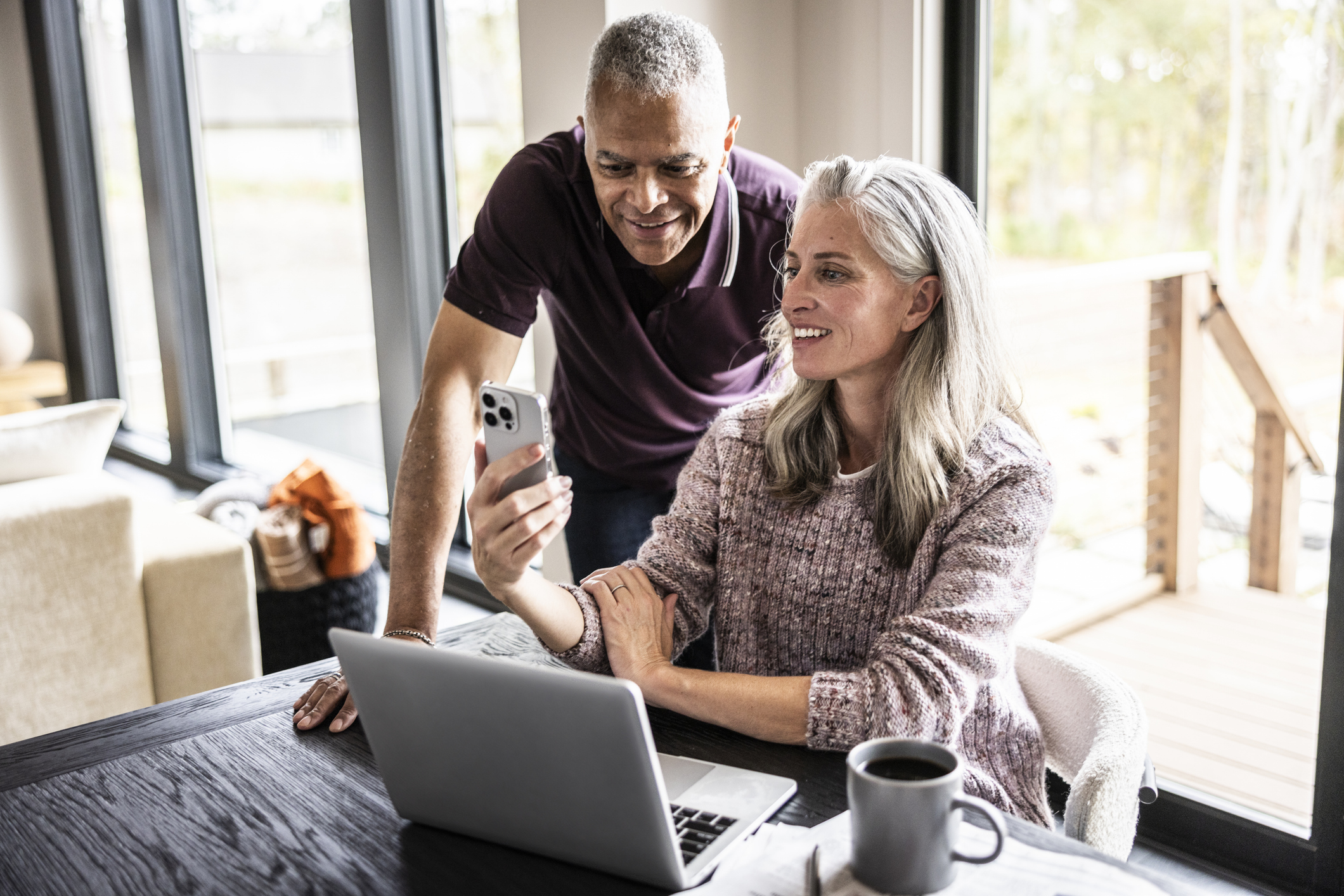 Senior couple using laptop and smartphone at home