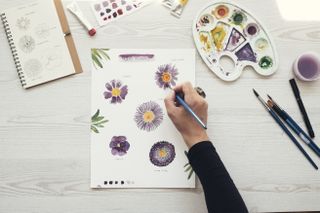 Woman painting flowers with water colors, top view