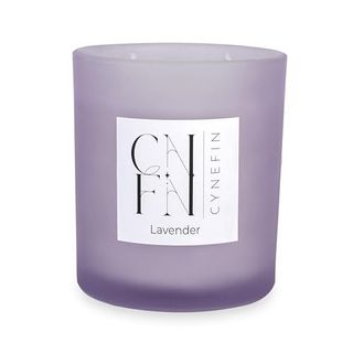 A purple glass candle jar with a lit two wick candle inside. 