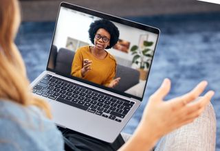 A woman is on a video call with her therapist on a laptop