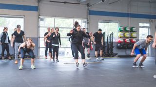 Group of people performing broad jumps in a gym