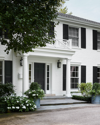 A simple porch and stately columns with boxwoods on the low hedges, pear trees and white impatiens