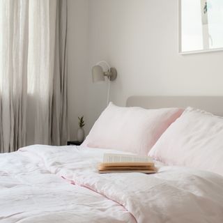 how to decorate a guest bedroom, pale pink and pale grey bedroom, pale pink linen bedding, grey wall light, grey bed and curtains