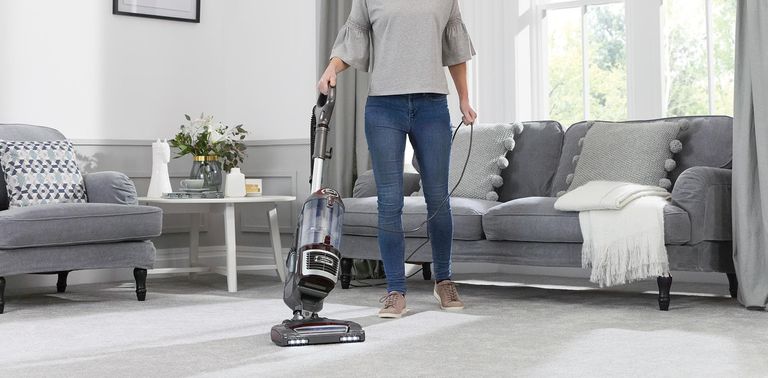 a woman vacuuming with a shark vacuum cleaner in a living room