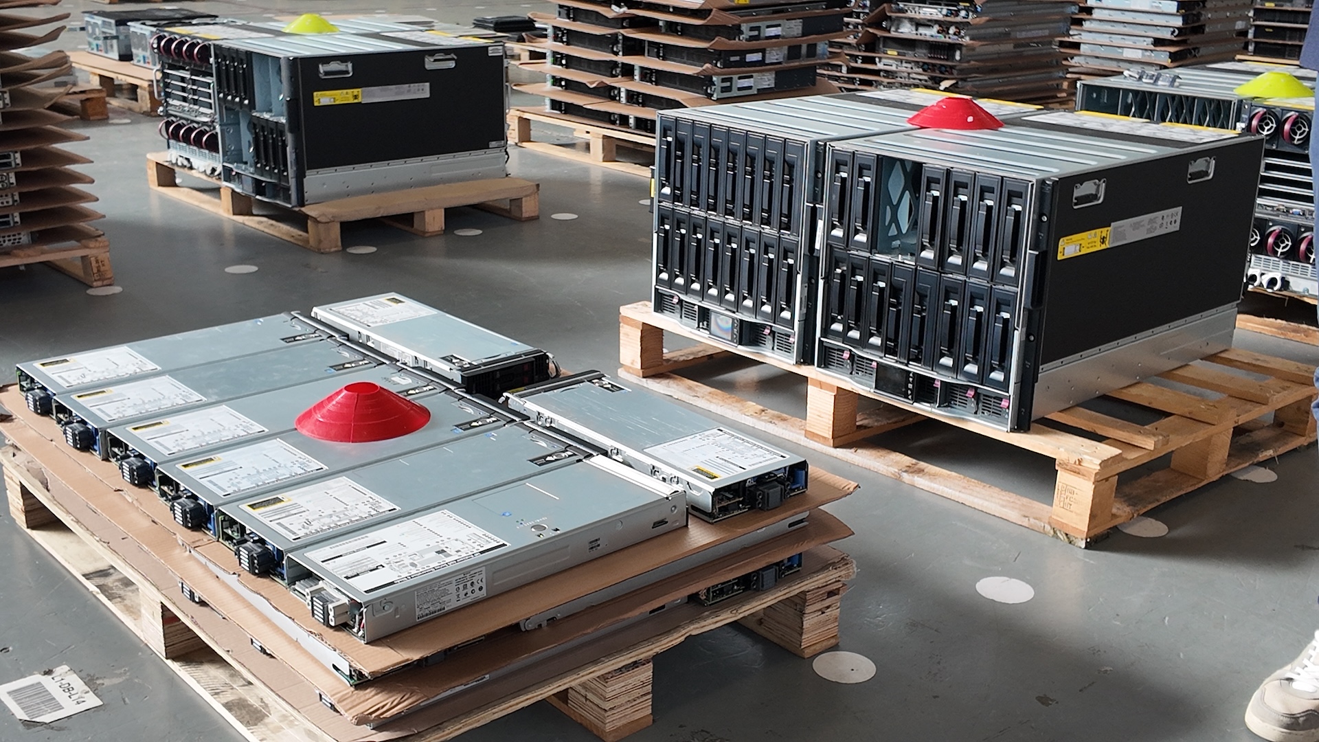 Several server GPUs are arranged neatly on a pallet with a red cone on top to signify process stage.