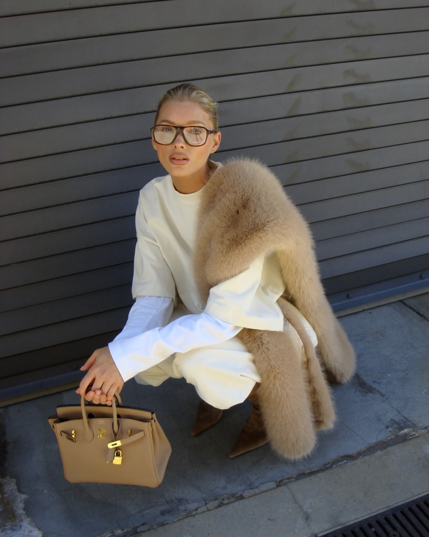 Elsa Hosk wearing a butter yellow sweatshirt and sweatpants with tan boots, a tan fur scarf, and a tan Birkin bag.