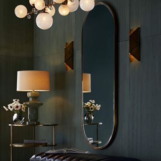 Dark hallway with long curved mirror on wall next to console table