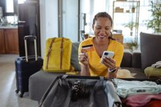 Woman packing for a trip and using online payment services