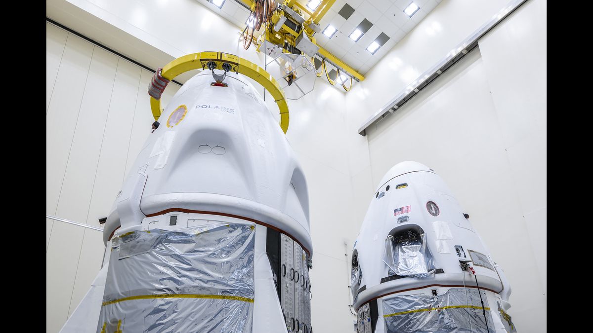 two white space capsules are seen inside a large, white-walled room