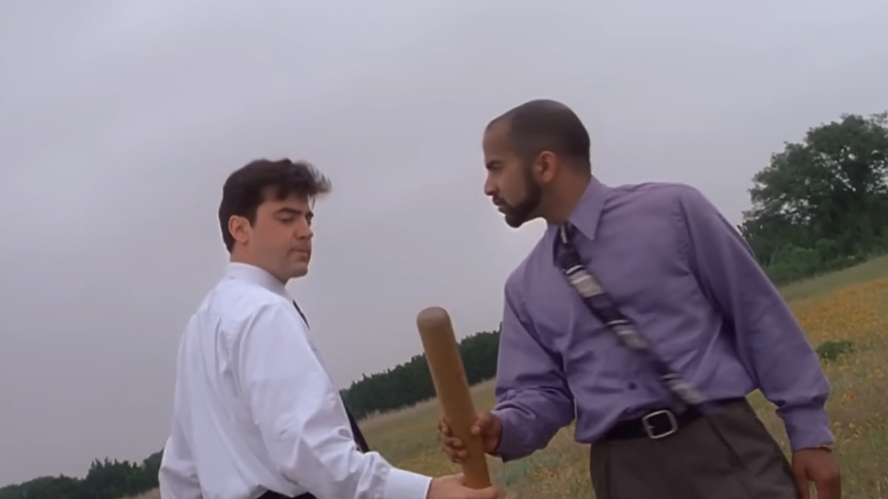 Ron Livingstone in a shirt and tie handing a baseball bat to another man in a shirt and tie in Office Space