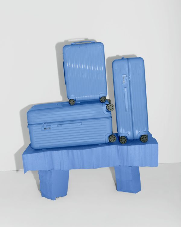 A sea blue minimalist cabin suitacase is captured in multiple sun-lit settings.