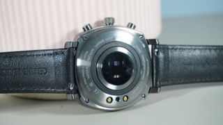 The Pininfarina Senso Hybrid smartwatch on a grey background against a pink plant pot