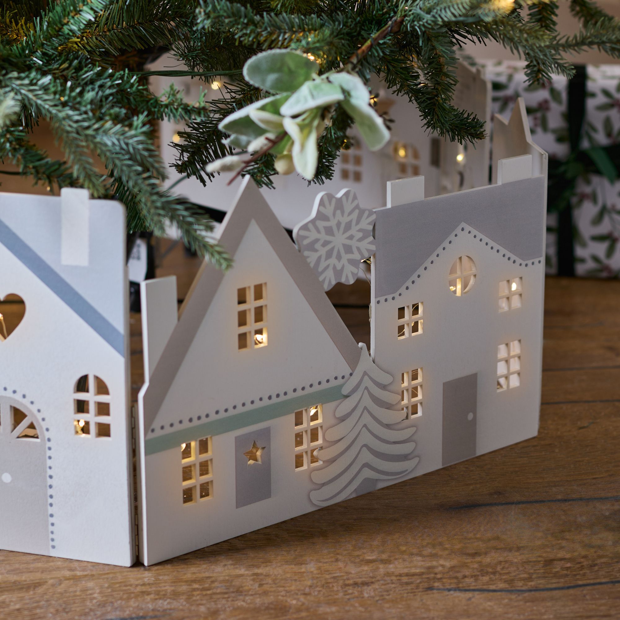 A white wooden tree skirt from Next, designed to look like a row of Christmas houses