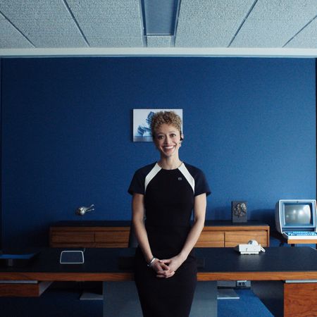 Sydney Cole Alexander as natalie smiling and posing in a lumon office in severance