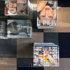 Glass topped coffee table propped up with marble and stacks of magazines including Vogue and Pop