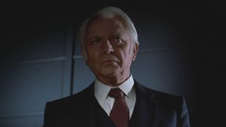 Dan O'Herlihy looking stern as he stands partially obscured by darkness in Halloween III: Season of the Witch.