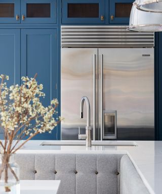 A kitchen with dark blue cabinets and a stainless steel fridge