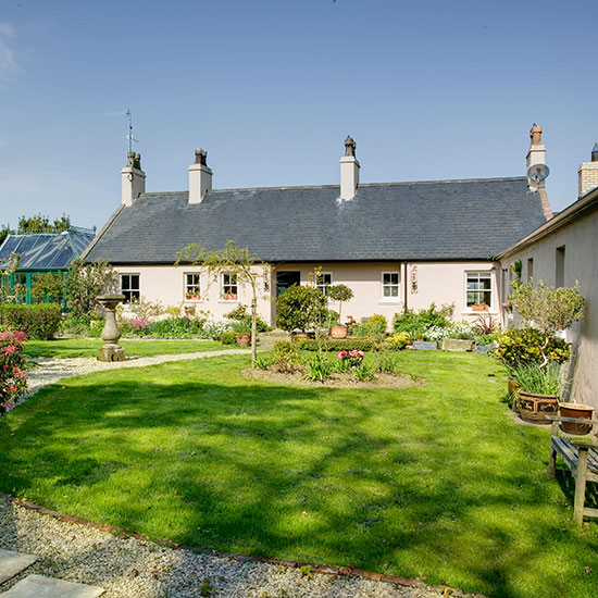 sloping roof house with white windows and grass lawn