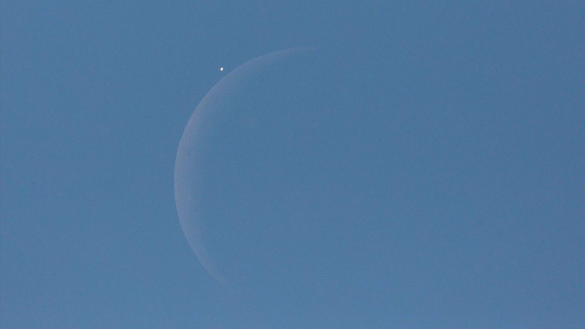 An image of the moon and Venus in a blue sky.