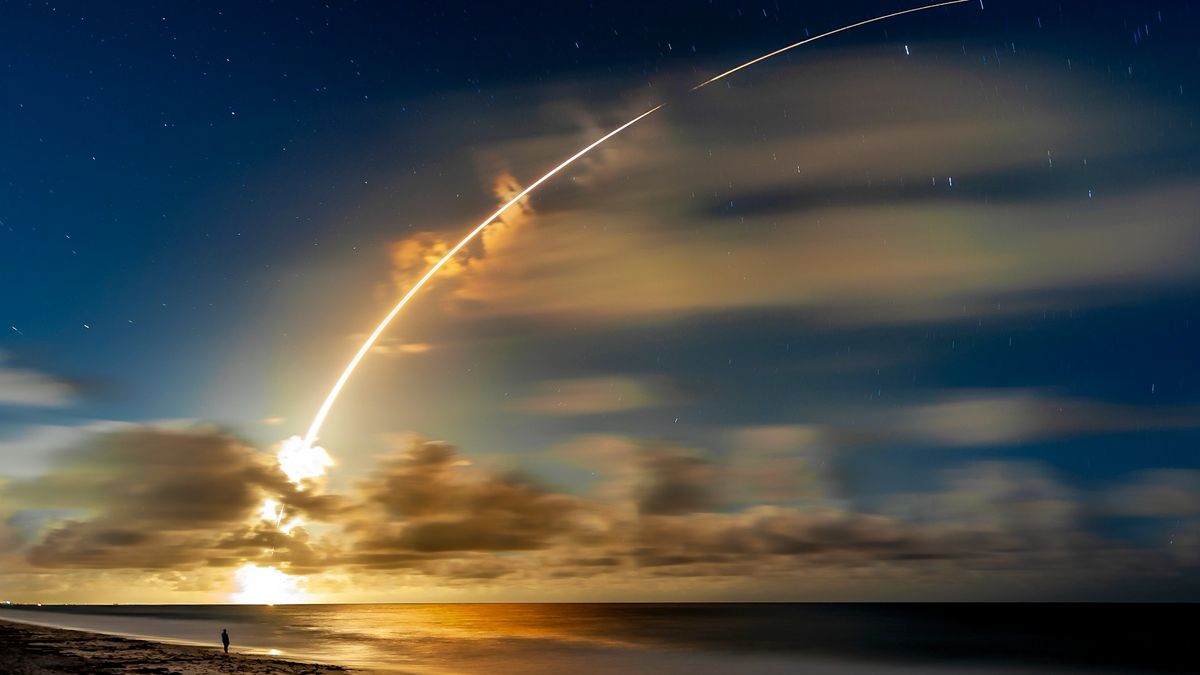 a rocket launches over a beach at sunset