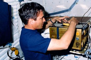 STS-29 astronaut John Blaha works with the "Chix in Space" egg incubator aboard the space shuttle Discovery in 1989.