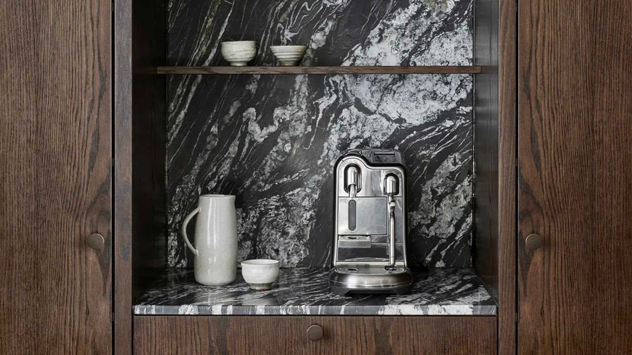 a sage espresso maker in a marble and wood kitchen