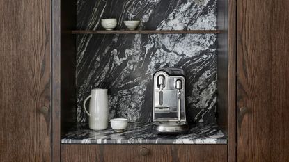 a sage espresso maker in a marble and wood kitchen