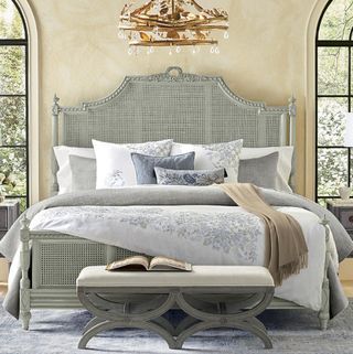 A luxurious bed with a grey headboard and chandelier over it