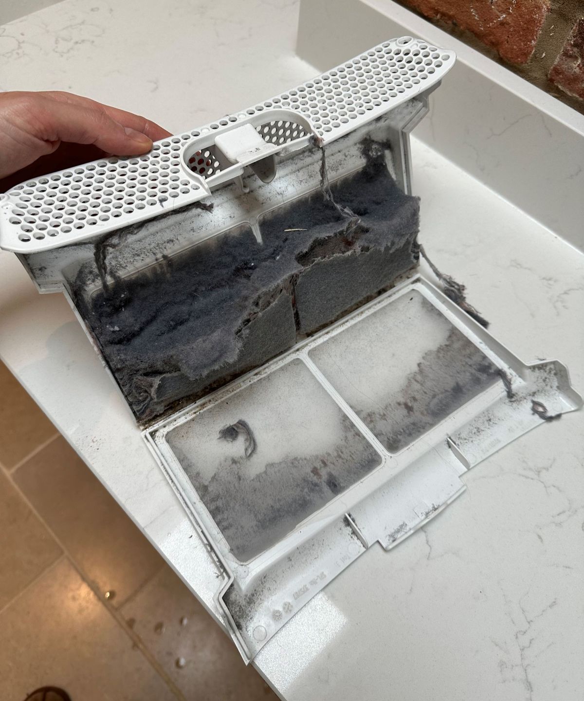 Opening up a lint collector to see the lint that has collected inside