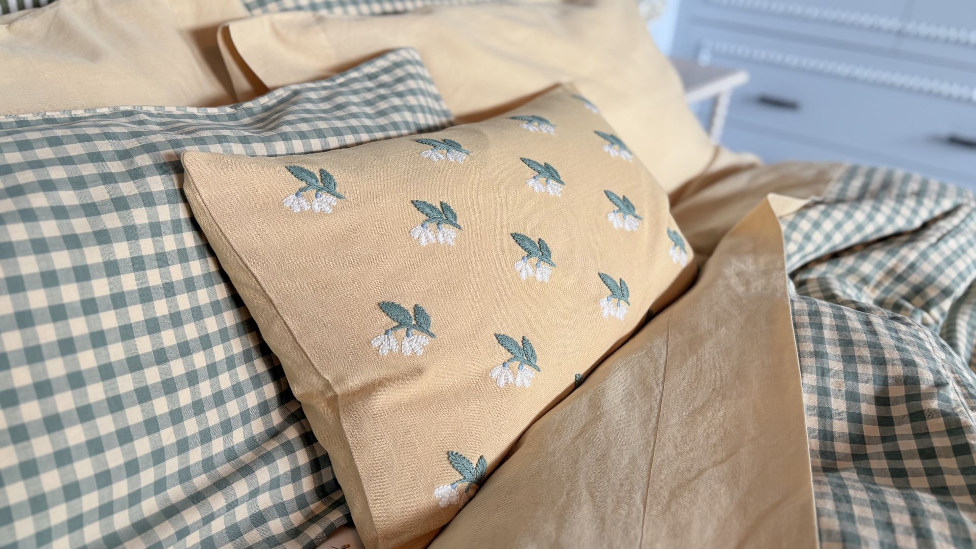 piglet in bed bedding with throw cushions that are embroidered and gingham sheets