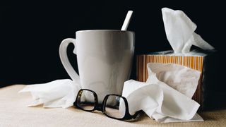 Mug, box of tissues, pair of glasses on a table