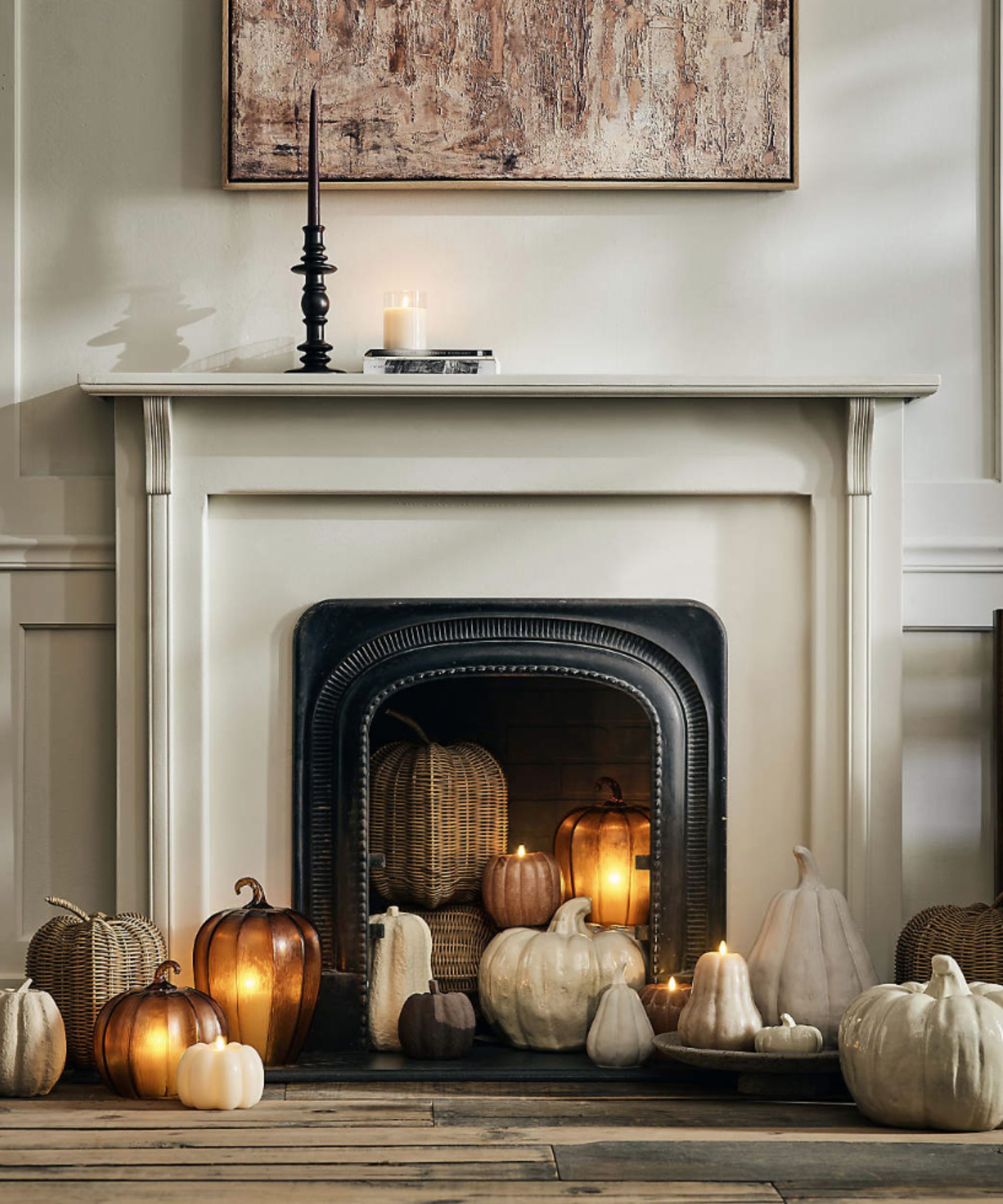 Fireplace full of neutral toned pumpkins and candles